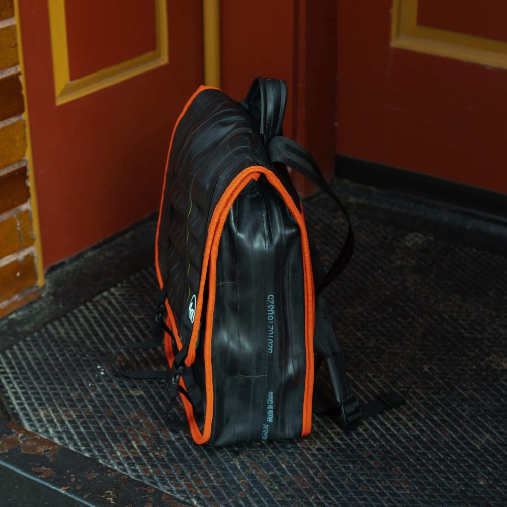 Madison Upcycled Backpack by Alchemy Goods. Black and Mandarin. Left view.